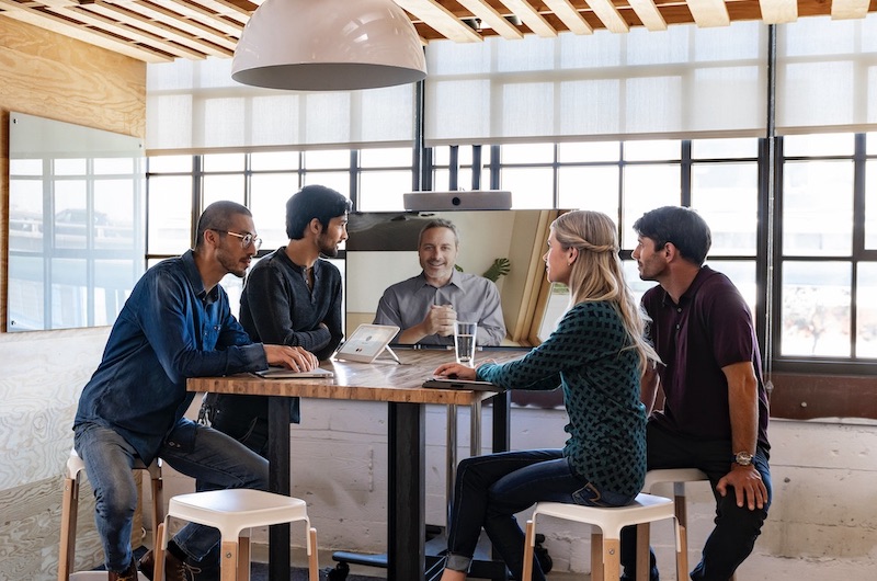 Ein Team arbeitet über das Room Kit mit einem Kollegen online zusammen