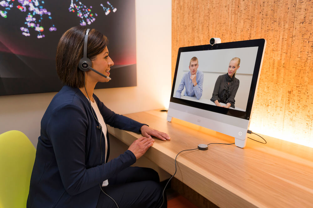 Eine Frau nutzt das kabelgebundene Headset und die DX80 für ihr Onlinemeeting