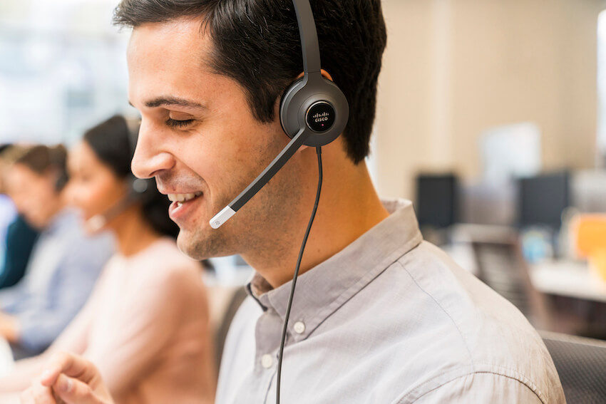 Ein Mann telefoniert über sein kabelgebundenes Headset im Büro