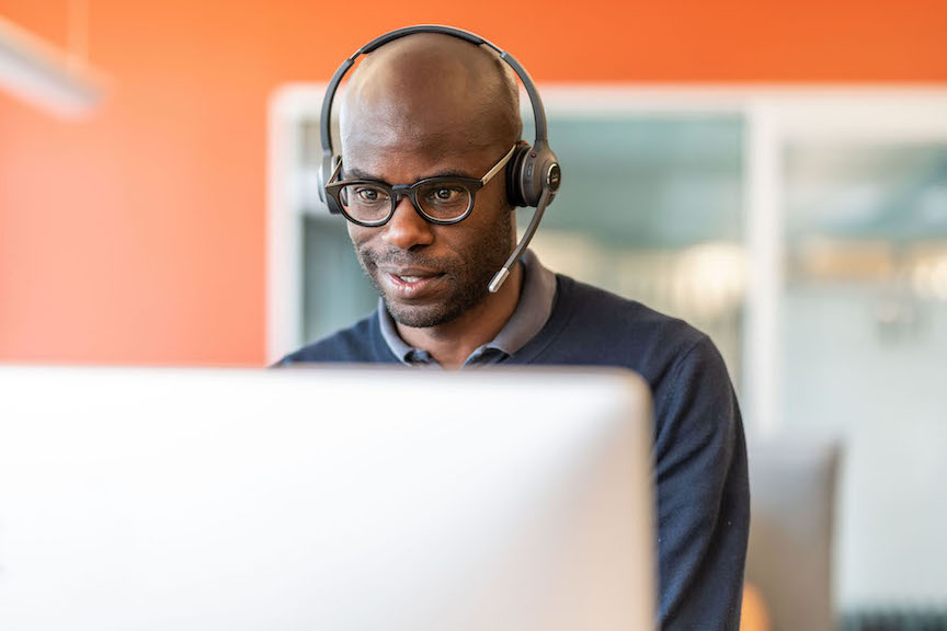 Ein Mann telefoniert über das Headset und gibt gleichzeitig Daten in den Computer ein